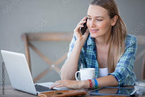 Young Woman Working on Laptop and Talking on Phone