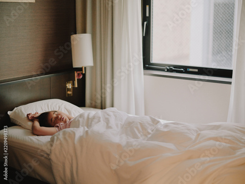 Young child sleeping peacefully in a hotel bed in morning light