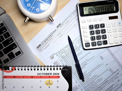 US tax return form 1040 with October 2026 calendar and calculator on office desk top view