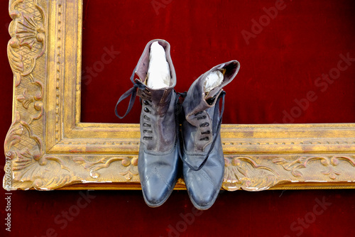 Pair of antique leather boots displayed on a gilded frame 