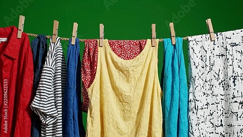 Colorful laundry hanging on clothesline against green background motion video footage clip
