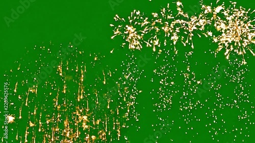 Bright golden fireworks exploding against a solid vibrant green screen background captured in high-motion video footage