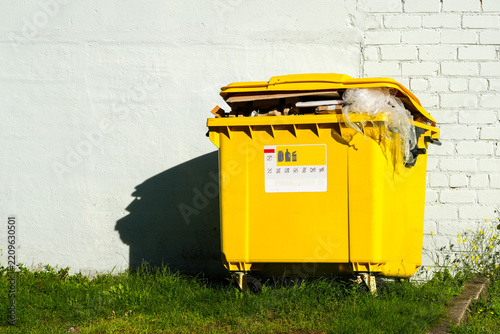 Overflowing Yellow Recycling Container Filled With Cardboard and Plastic Waste Outdoors
