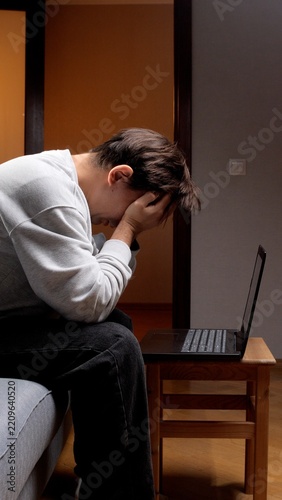 Obraz na plátně Man feeling frustrated and depressed, covering his face with hands while sitting