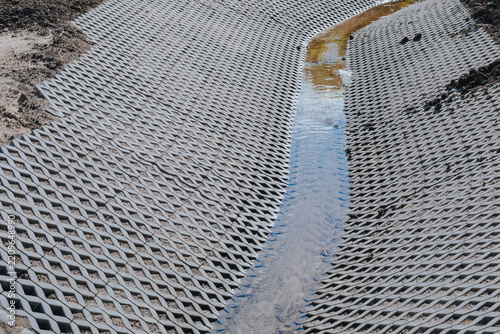 Concrete erosion control grid with drainage channel and flowing water at a construction site