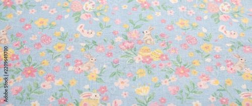 Pastel floral cotton Easter fabric texture. Printed linen with cute bunnies, eggs, and spring blossoms. Light blue textile background