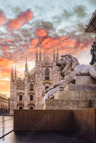 Iconic lion statue guards Milan's Duomo beneath a dramatic dawn sky