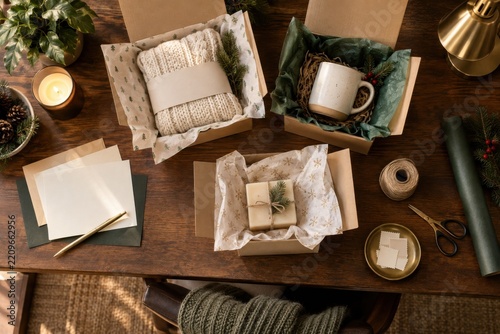 A home business packing desk with three handmade products in blank boxes and seasonal tissue paper for festive holiday marketing and editorial use
