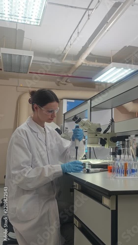 Lab or laboratory. Female scientist conducting laboratory research using lab tools. Such as microscope pipette and laptop to analyze samples and colorful bio chemical solutions in a modern laboratory