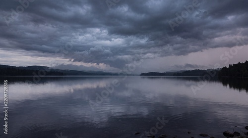 Moody dark storm clouds reflecting over a calm mountain lake