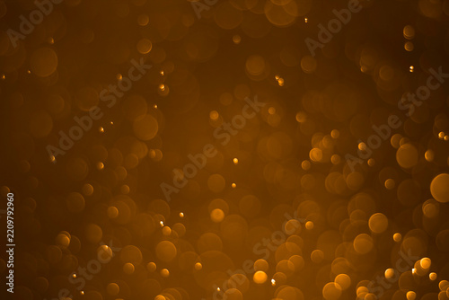 Abstract blurred background with golden bokeh lights on a dark background.