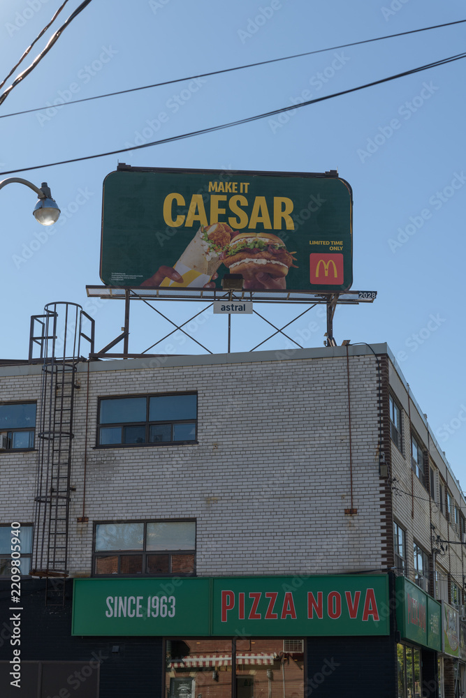 Fototapeta premium traditional rooftop billboard with McDonald's Canada ad for Caesar atop Pizza Nova, a pizza restaurant chain, located here at 645B Mount Pleasant Rd, Toronto