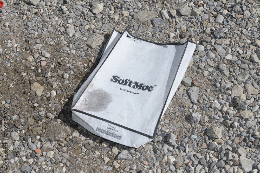 Fototapeta premium grungy, discarded bag with SoftMoc logo on a gravel ground in Toronto