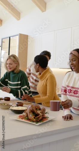 Vertical video: Mug placing starting Diverse friends serving dinner at kitchen island by turkey