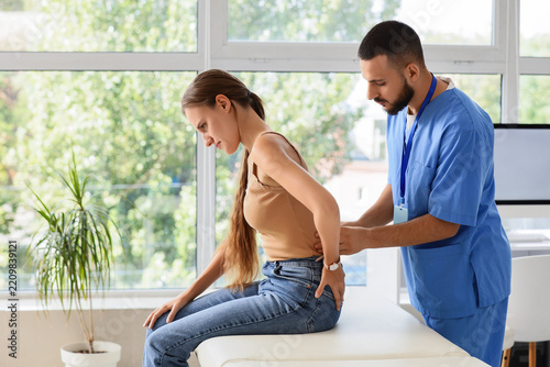 Back pain treatment and physical therapy, male chiropractor examining female ...