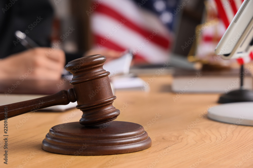 Fototapeta premium Legal justice and judicial system, wooden judge gavel on courtroom desk with American flag and lawyer working in background for law and order