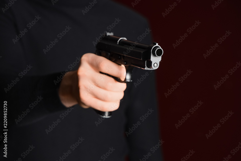Fototapeta premium Gun violence and crime prevention, person holding a black handgun in a dark room for security and self defense