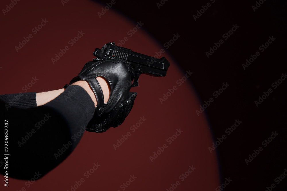 Obraz premium Crime and violence prevention, person in black leather gloves holding a handgun in a dark room with dramatic spotlight for thriller movie production