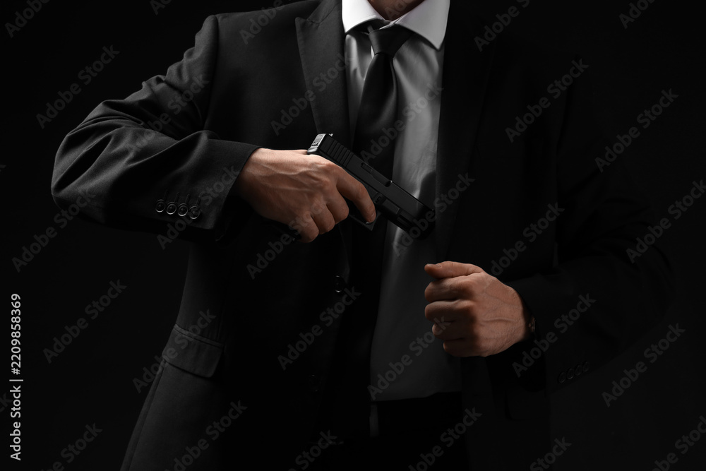 Obraz premium Security and executive protection, bodyguard in suit drawing a handgun for defense and law enforcement operations in a dark professional environment