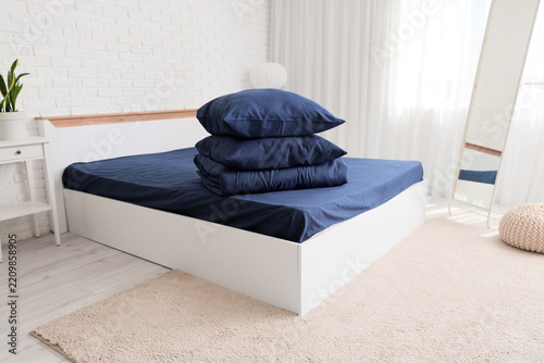 Sleep hygiene and bedroom comfort, stack of blue pillows and bedding on a whi...