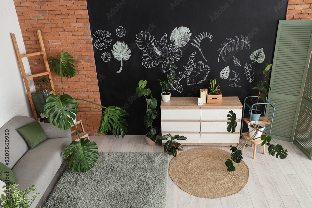 Fototapeta premium Biophilic interior design and home decor, modern living room with monstera plants and botanical chalk wall art in a cozy apartment with brick wall