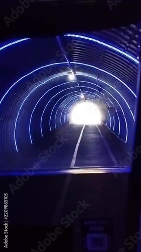Golf cart POV driving through illuminated tunnel exit light