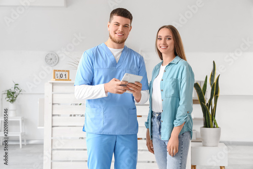 Healthcare consultation and patient care, male doctor in scrubs with tablet a...
