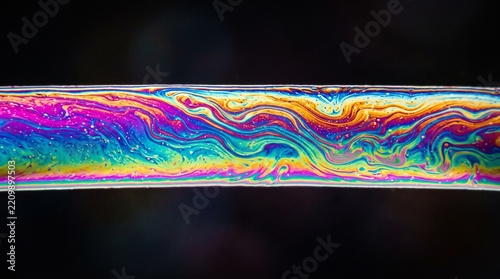 Iridescent soap film band showing rainbow interference colors and fluid motion
