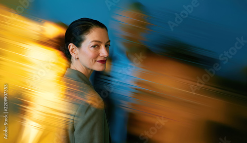 Modern Businesswoman Standing Calm Within Dynamic Yellow and Blue Motion Streaks