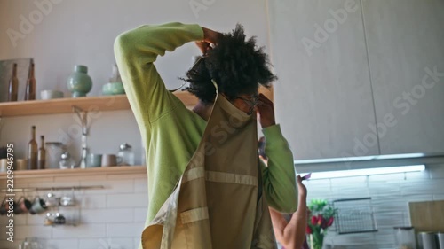 Man taking off apron kitchen dancing. Girlfriend embracing partner home cooking.