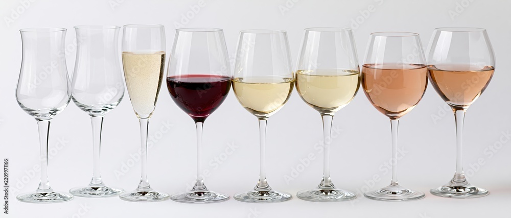 Obraz premium Seven wine and champagne glasses in a row filled with different colored wines against a white background