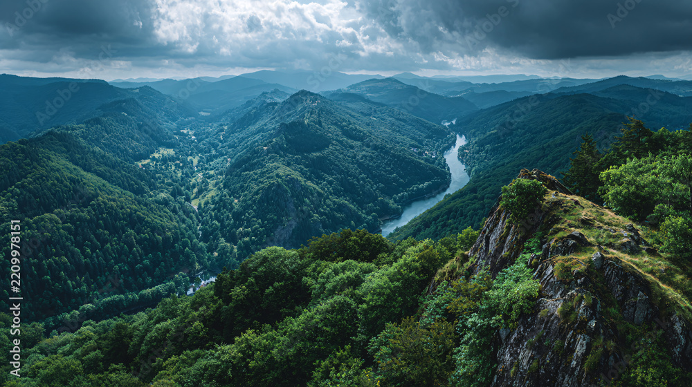 Obraz premium Expansive View of Lush Green Mountain Landscape with River and Dramatic Clouds