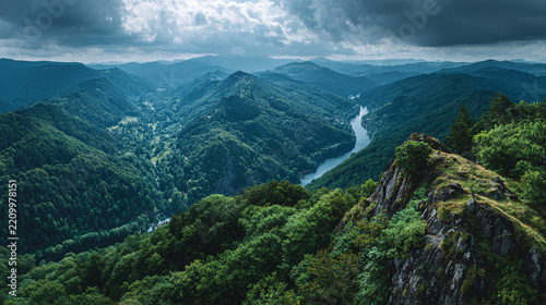 Expansive View of Lush Green Mountain Landscape with River and Dramatic Clouds