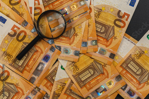 Magnifying glass on euro banknotes for money analysis and inspection