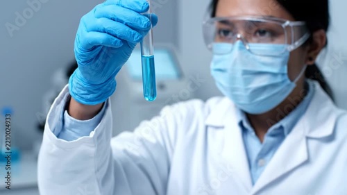 Scientist in lab with test tube and fluid.