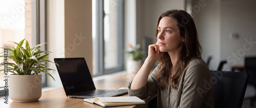 Thoughtful Businesswoman Sitting at Desk Looking Away
