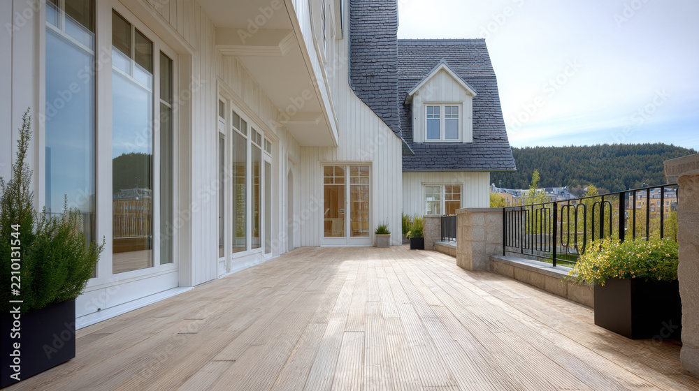 Fototapeta premium Spacious wooden terrace with modern white house, large windows, potted plants, and scenic mountain view