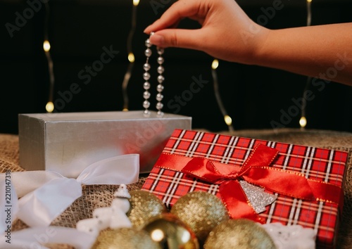 Elegant Christmas gift box with a red ribbon surrounded by golden baubles and white festive decorations,creating a warm holiday scene for Christmas gifting, seasonal advertising and winter celebration