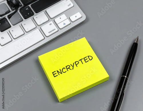 Bright Yellow Sticky Note with the Word Encrypted Next to a Silver Keyboard and Pen