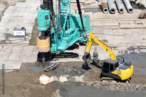 大型建築物の杭基礎工事で杭施工機による掘削と油圧ショベルで排土する作業
