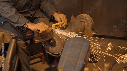 Craftsman Sharpening Metal Tool on Bench Grinder in Workshop