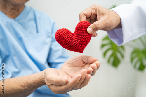 Asian elder senior woman patient holding red hear and give to doctor t in hospital.