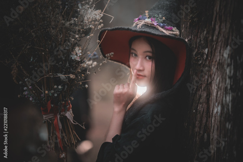 Fotografie Mysterious Woman Wearing Wide Brim Hat In Dark Woodland Witch costume Halloween Themes
