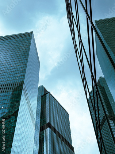 Glass skyscrapers rise against a cloudy sky