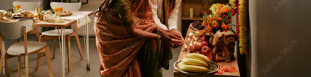 Obraz premium Header of Indian young adult couple celebrating Diwali festival by lighting oil lamps together indoors. Image represents cultural tradition and holiday celebration for festive marketing campaigns
