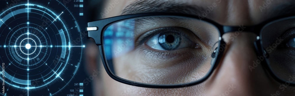 Obraz premium Close up of radar operator eye behind glasses. Military specialist analyzes drone detection data on digital tactical screen. Soldier monitors UAV movement using advanced surveillance system,