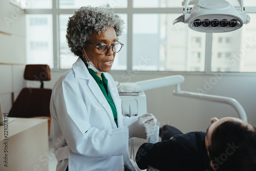 Dentist consulting senior patient during dental checkup in a modern clinic