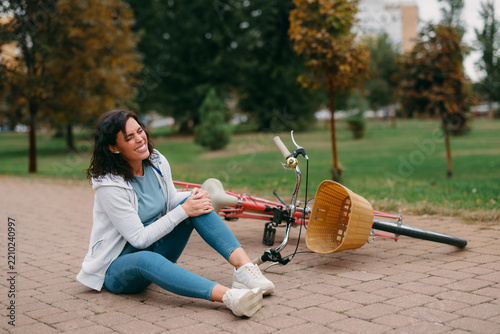 Woman experiencing knee pain after falling off bicycle