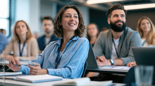 Engaged Audience: A diverse group of professionals attentively listens during a business seminar or workshop, with a woman in the foreground smiling and engaged.