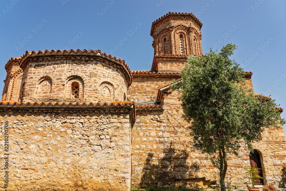Fototapeta premium St Naum Monastery on the shore of Lake Ohrid in North Macedonia, with beautiful beaches, crystal clear blue water and scenic mountain landscape surrounding the historic religious site.